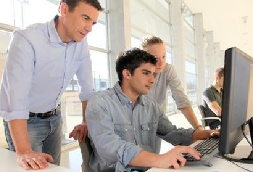 Junger Mann wird am Computer eingeschult